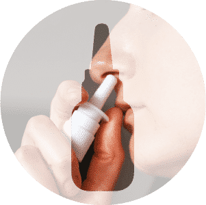 Personne utilisant un spray nasal, tenant le flacon près de sa narine et pressant le pulvérisateur pour administrer le médicament.